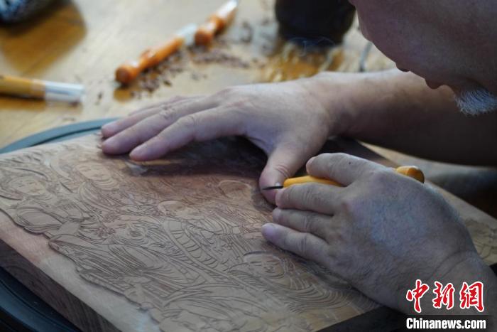 圖為徐晉林湊近木板，近距離制作雕版畫(huà)。　九美旦增 　攝