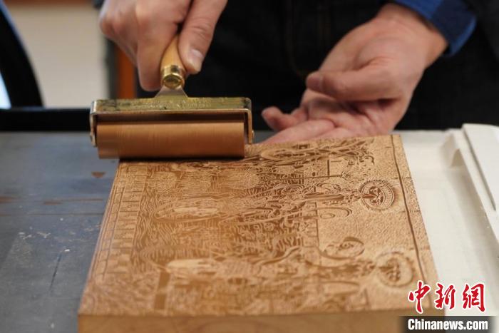 圖為徐晉林工作室工作人員正在給雕好壁畫(huà)的版面滾油墨?！【琶赖┰?　攝