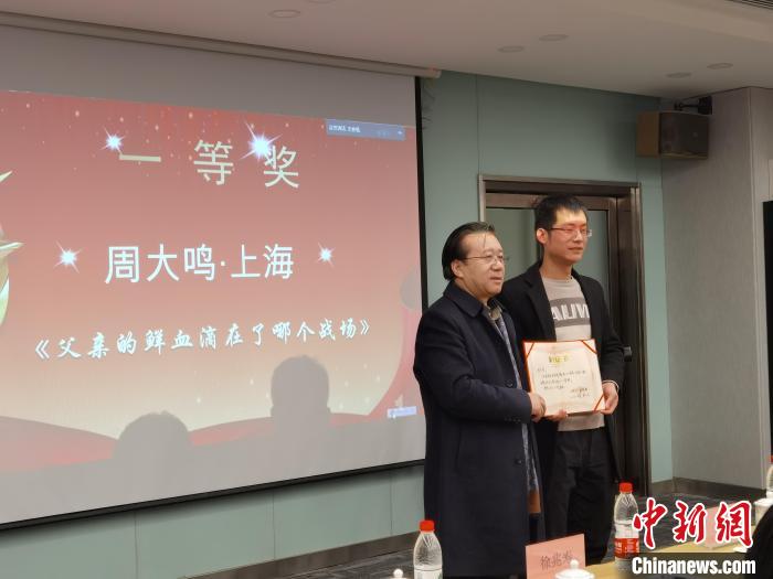 圖為作家、西北師范大學(xué)新聞與傳媒學(xué)院院長徐兆壽頒發(fā)一等獎證書，代領(lǐng)獎?wù)呱吓_領(lǐng)獎。　楊娜 攝