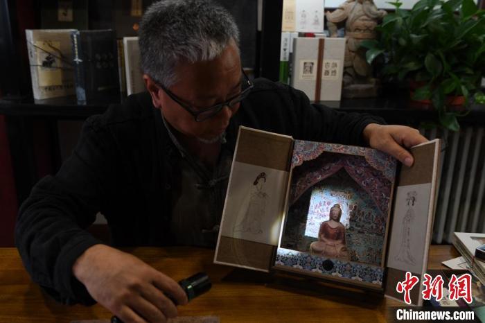 圖為讀者出版集團(tuán)讀者晉林工作室獨(dú)立出品人徐晉林，展示互動(dòng)性強(qiáng)的敦煌題材手工書(shū)。(資料圖) 楊艷敏 攝