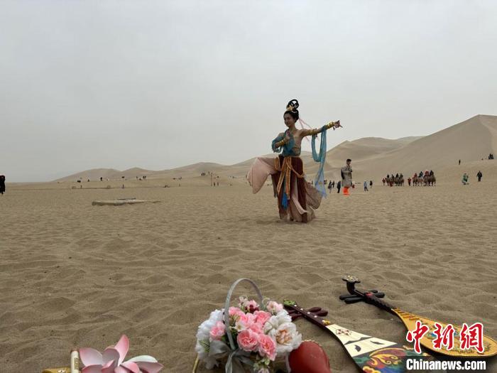 圖為2023年4月底，敦煌大漠“逐舞者”奧楠在鳴沙山月牙泉景區(qū)視頻直播敦煌舞?！●T志軍 攝