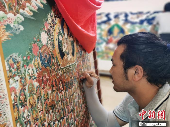 圖為更登才讓的徒弟繪畫(huà)唐卡?！?zhí)砀?攝