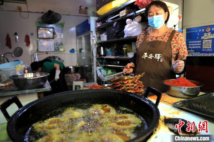 圖為平安驛·河湟民俗文化體驗(yàn)地內(nèi)的商戶炸干板魚?！⊙Φ?攝