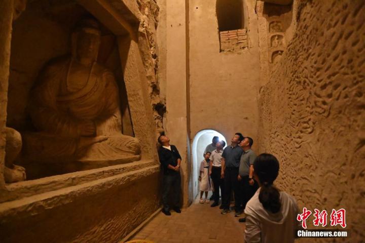 7月15日，游人參觀甘肅省平?jīng)鍪袥艽h百里石窟長廊中的王母宮石窟。百里石窟長廊位于涇川縣境內(nèi)，由512個(gè)石窟、5眼窟中石井組成，現(xiàn)存王母宮石窟、鳳凰山石窟、南石窟寺、丈八寺石窟、羅漢洞石窟、太山寺石窟等規(guī)模較大的石窟群，還有數(shù)量眾多的小石窟群。王母宮石窟又名千佛洞，該窟設(shè)計(jì)宏大，造像生動(dòng)，窟內(nèi)擁有造像數(shù)百尊，是較為珍貴的佛教文化歷史遺存。中新社記者 李亞龍 攝</p>
<p>